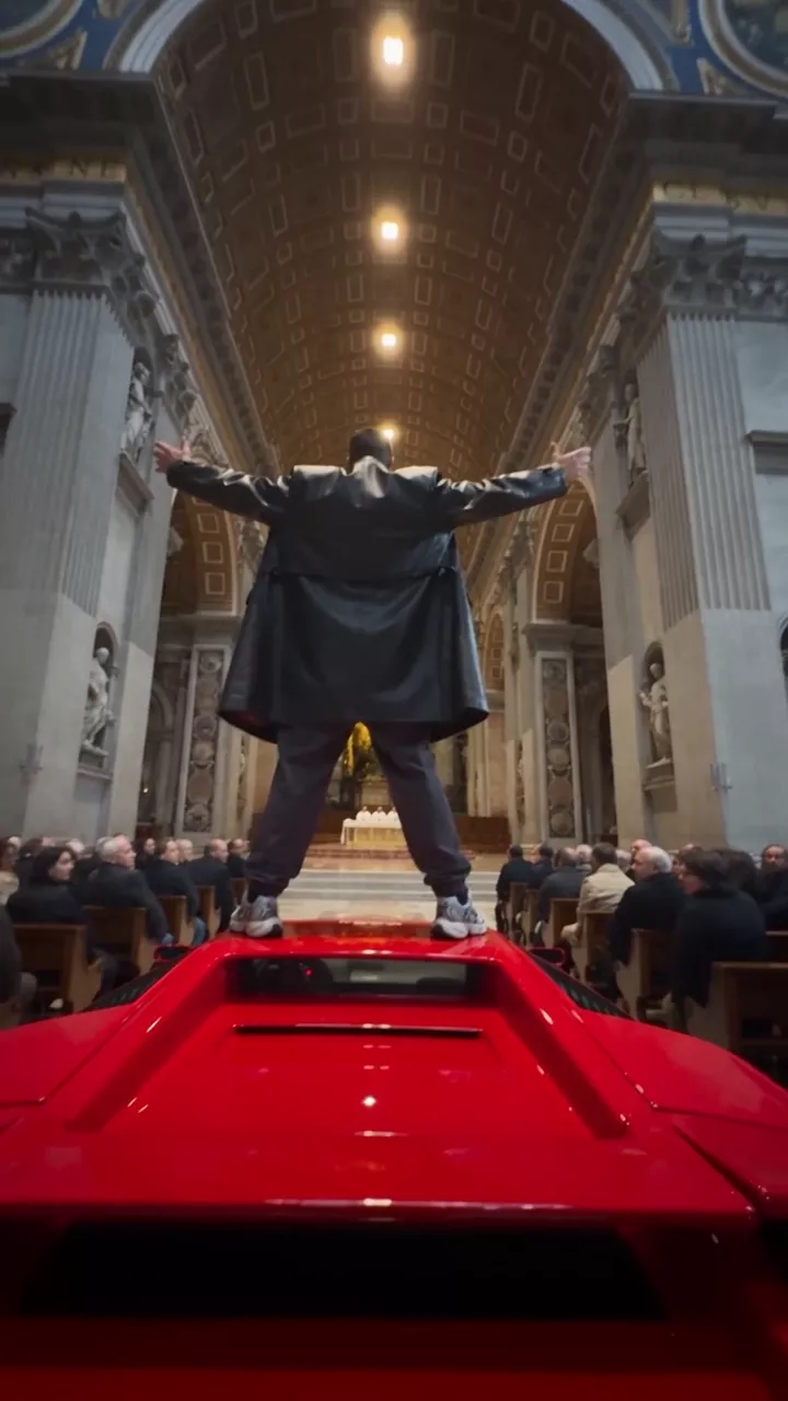 Inside a vast Roman church during a service: a man in a leather jacket stands on the roof of a red Lamborghini in the aisle with his arms spread, filmed low from behind, then a zoom to three shocked pastors at the altar, the congregation, and a wide view of the nave