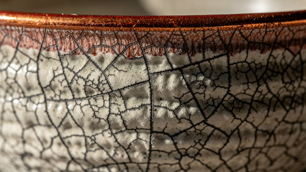Example made with FLUX.2 Max: An extreme close-up of a cracked ceramic glaze on a raku-fired bowl, the crackle lines filled with dark iron oxide, a rim of copper-red flashing…